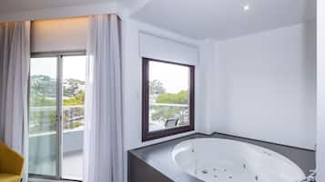 A modern bathroom with a freestanding bathtub, a large window with a view of the city, and a yellow chair.