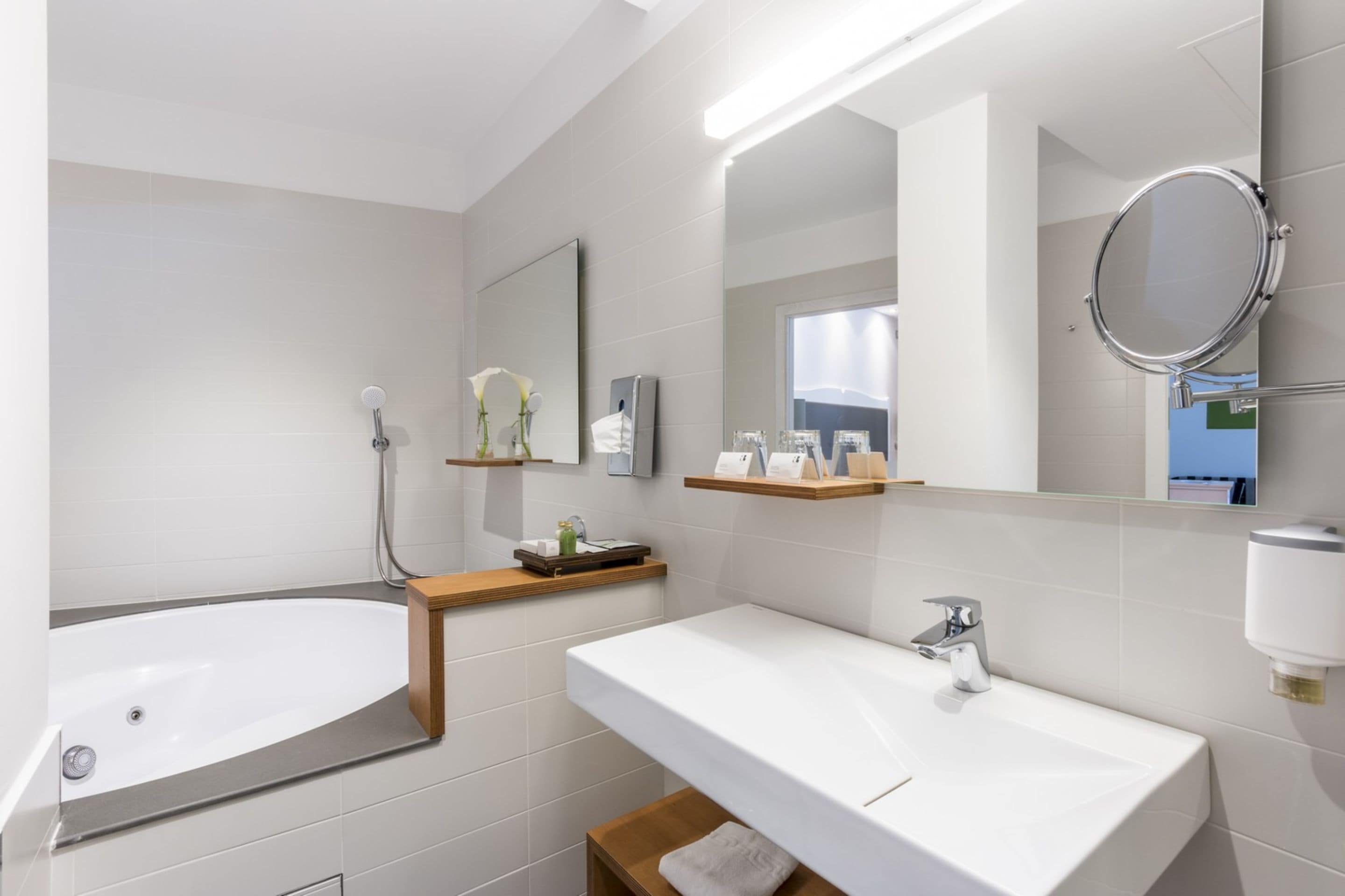 A modern bathroom with a bathtub, a sink, and a mirror.