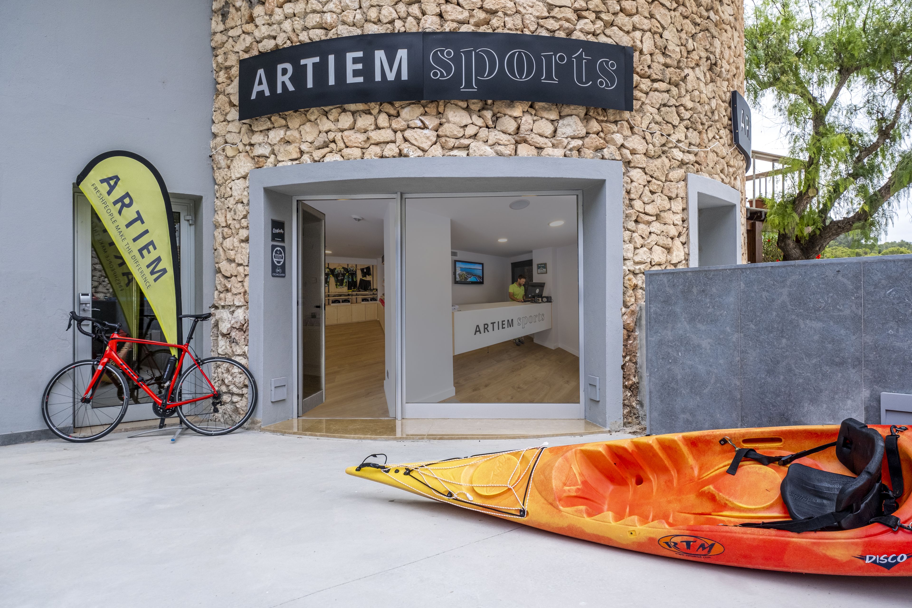 Un edificio con fachada de piedra y un letrero que dice 'ARTIEM SPORTS'.