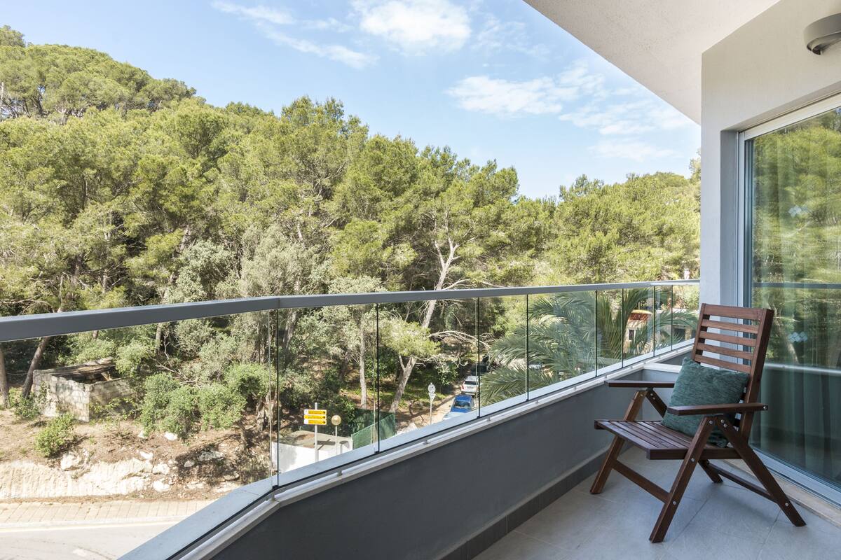 Un balcon avec une chaise en bois et une vue sur une zone boisée.