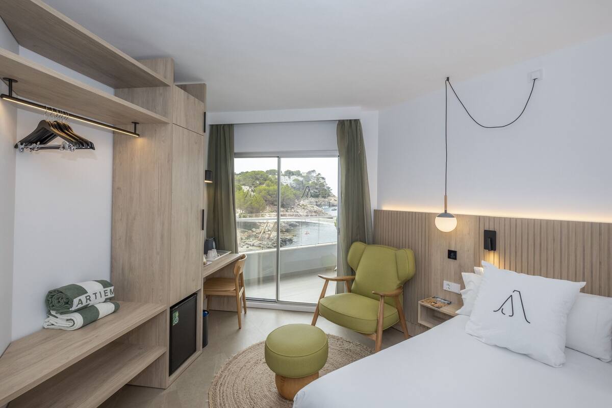 Une chambre d’hôtel moderne équipée d’un lit, d’un bureau, d’une chaise et offrant une vue sur l’extérieur.