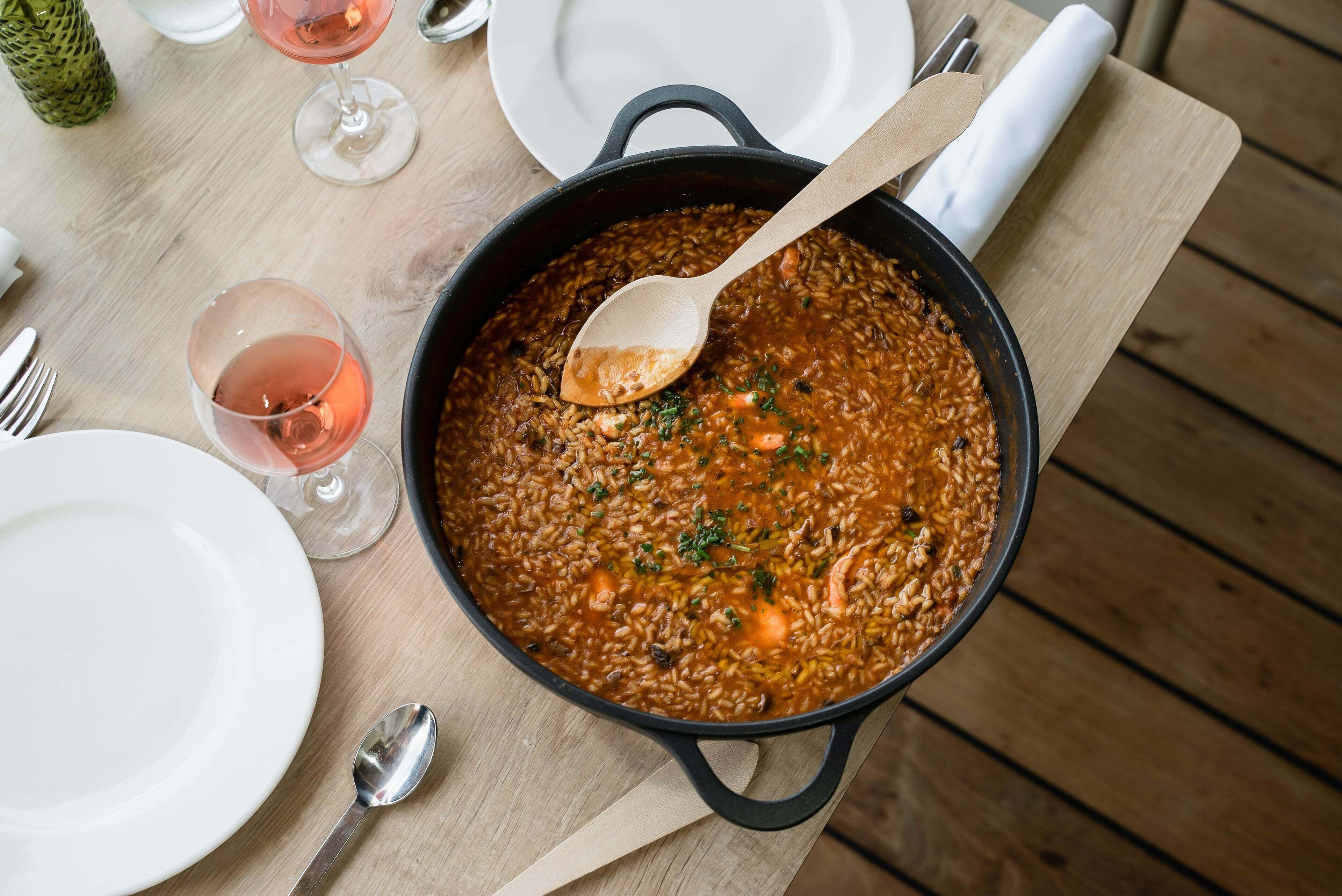 Une table à manger avec un plat de ragoût, un verre de vin et des assiettes blanches.