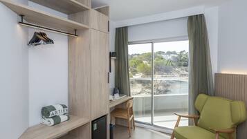 Una habitación moderna con escritorio, silla y vistas a un balcón.
