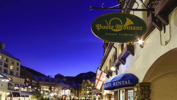 A nighttime view of a street with a sign for Posten Montane Luxury Lodging and a Skate Rental shop.