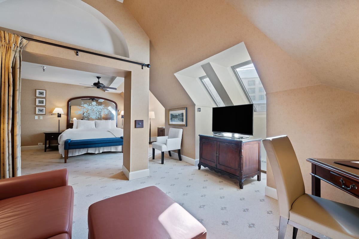A hotel room with a bed, a desk, a television, and a chair.