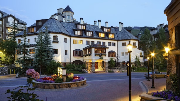 A large, multi-story hotel with a prominent tower, a landscaped driveway, and a well-lit entrance. - Poste Montane Lodge (Avon)