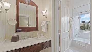 Une salle de bain avec un double vasque, un grand miroir, un porte-serviettes et une vue sur l’extérieur par une fenêtre.