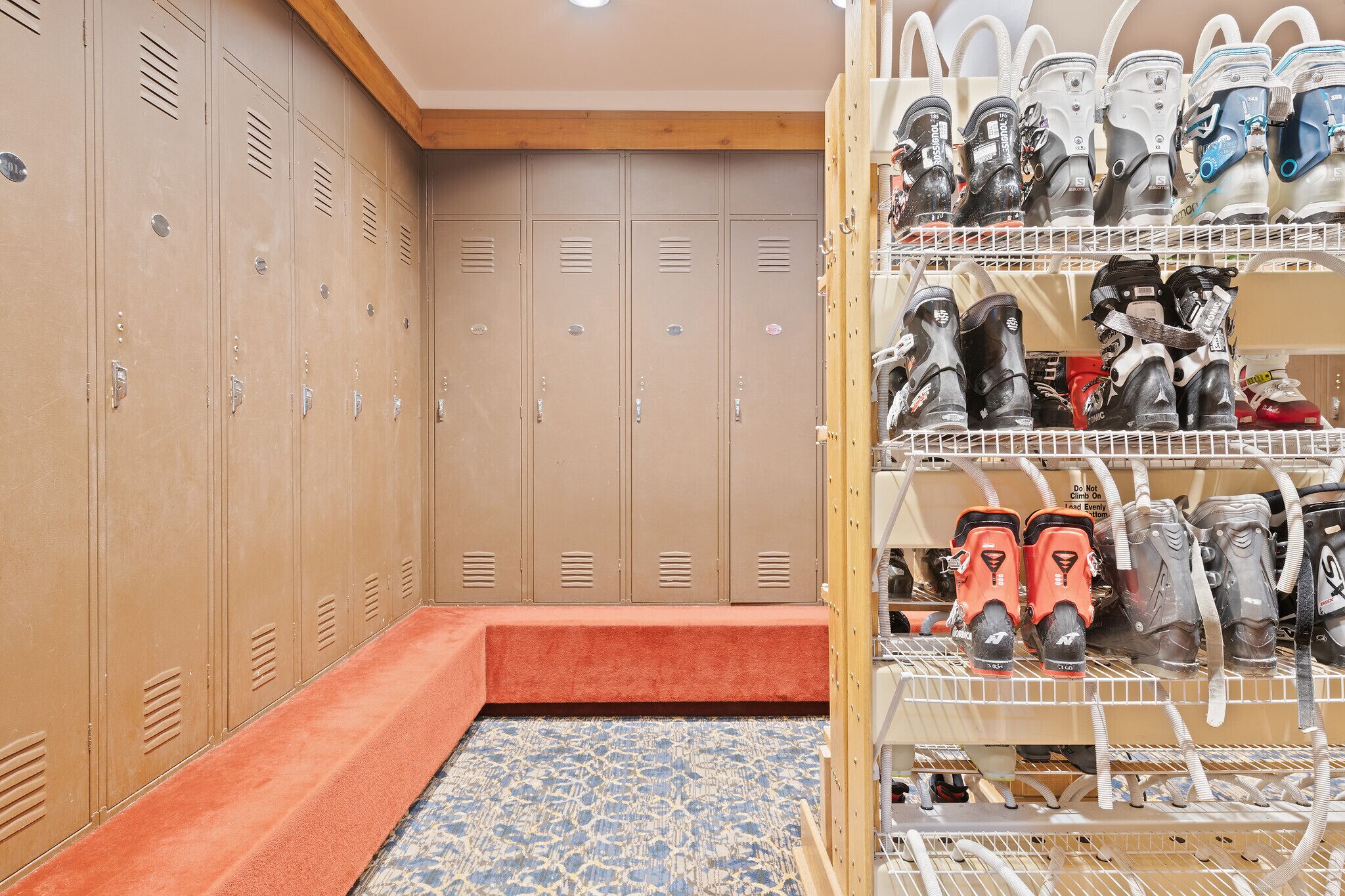 A locker room with multiple lockers and a shoe rack with various types of footwear.