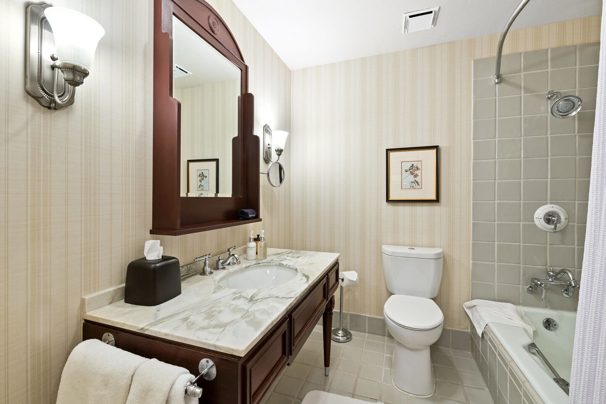 A bathroom with a marble sink, a large mirror, a toilet, and a shower with a glass door.