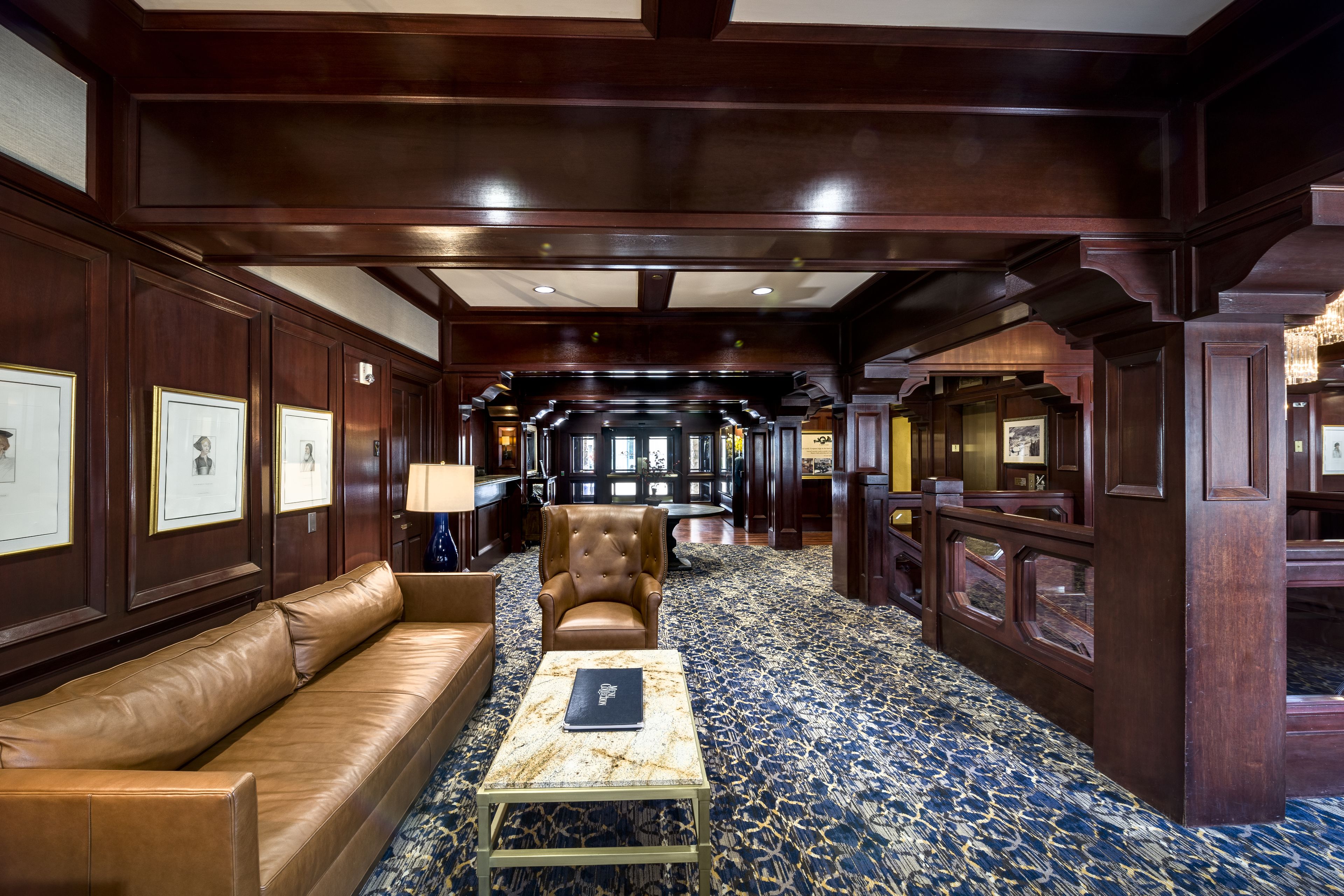 A luxurious lobby with a leather sofa, a tufted armchair, and a marble coffee table.