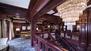 A grand lobby with a chandelier, wooden paneling, and a patterned carpet. - Poste Montane Lodge (Avon)
