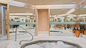 A spa area with a hot tub, wooden doors, and a seating area with chairs and vases. - Poste Montane Lodge (Avon)