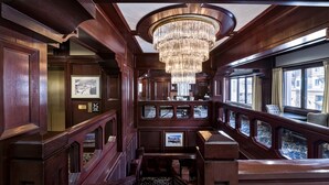 A luxurious train carriage with a grand chandelier, wooden paneling, and large windows offering city views. - Poste Montane Lodge (Avon)