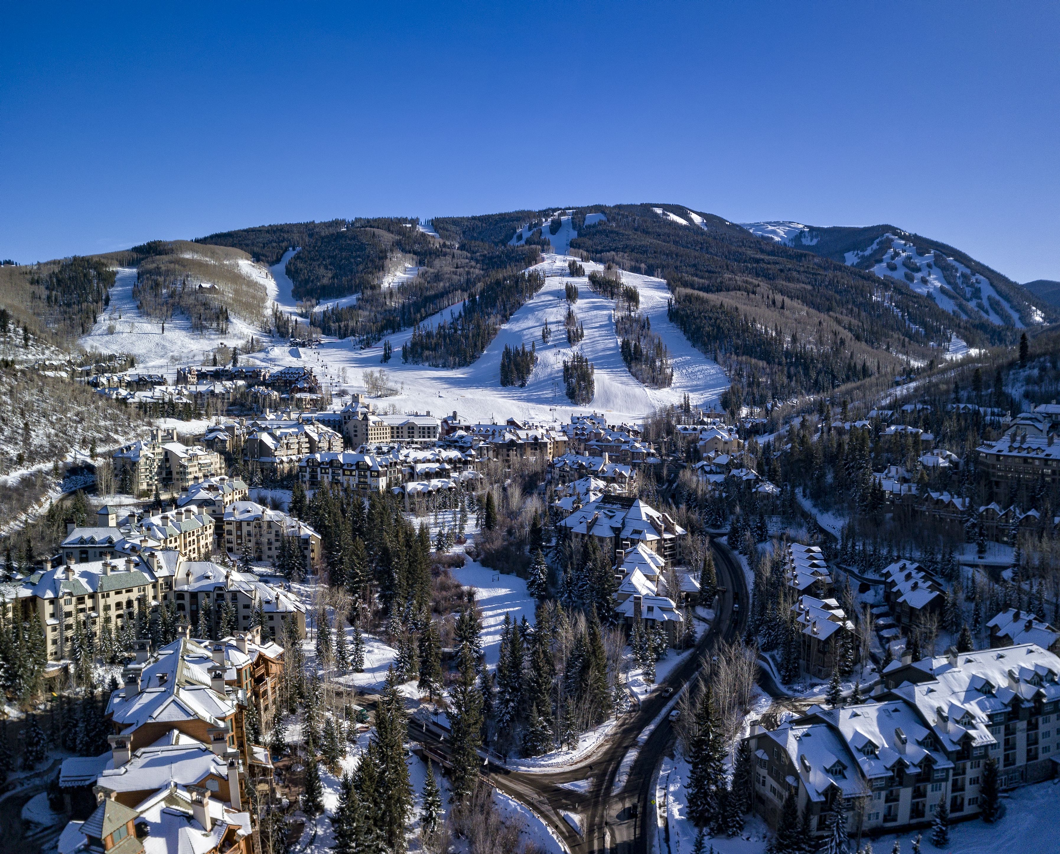 A snow-covered mountain town with a ski resort, including buildings with snow-covered roofs and a winding road.