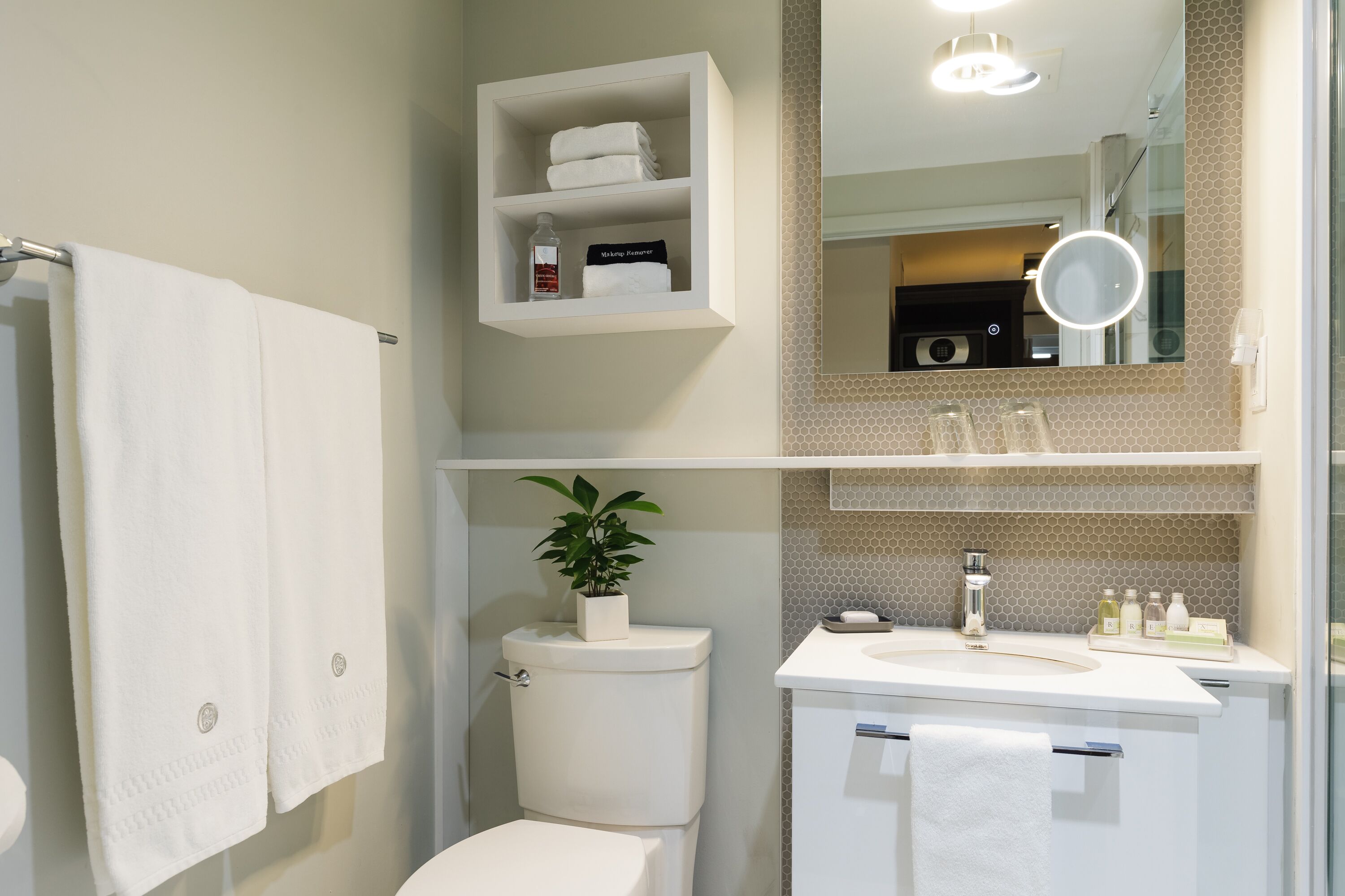 A modern bathroom with a toilet, sink, and a shelf with toiletries.
