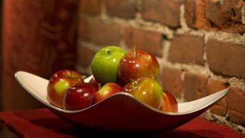 Un tazón de manzanas sobre un paño rojo, un muro de ladrillo y una pintura de fondo.