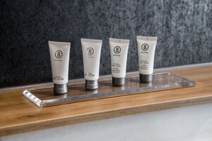 Four tubes of body lotion on a wooden shelf against a textured wall.