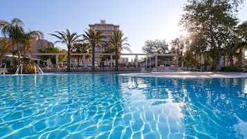 Een binnenzwembad, een buitenzwembad en parasols bij het zwembad