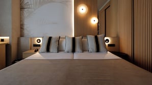 Une chambre d’hôtel moderne avec un grand lit, deux tables de chevet et des lampes fixées au mur.