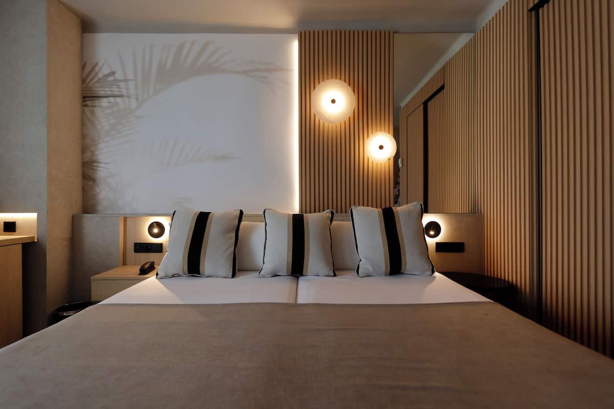 Ein modernes Hotelzimmer mit einem großen Bett, zwei Nachttischen und Wandleuchten.