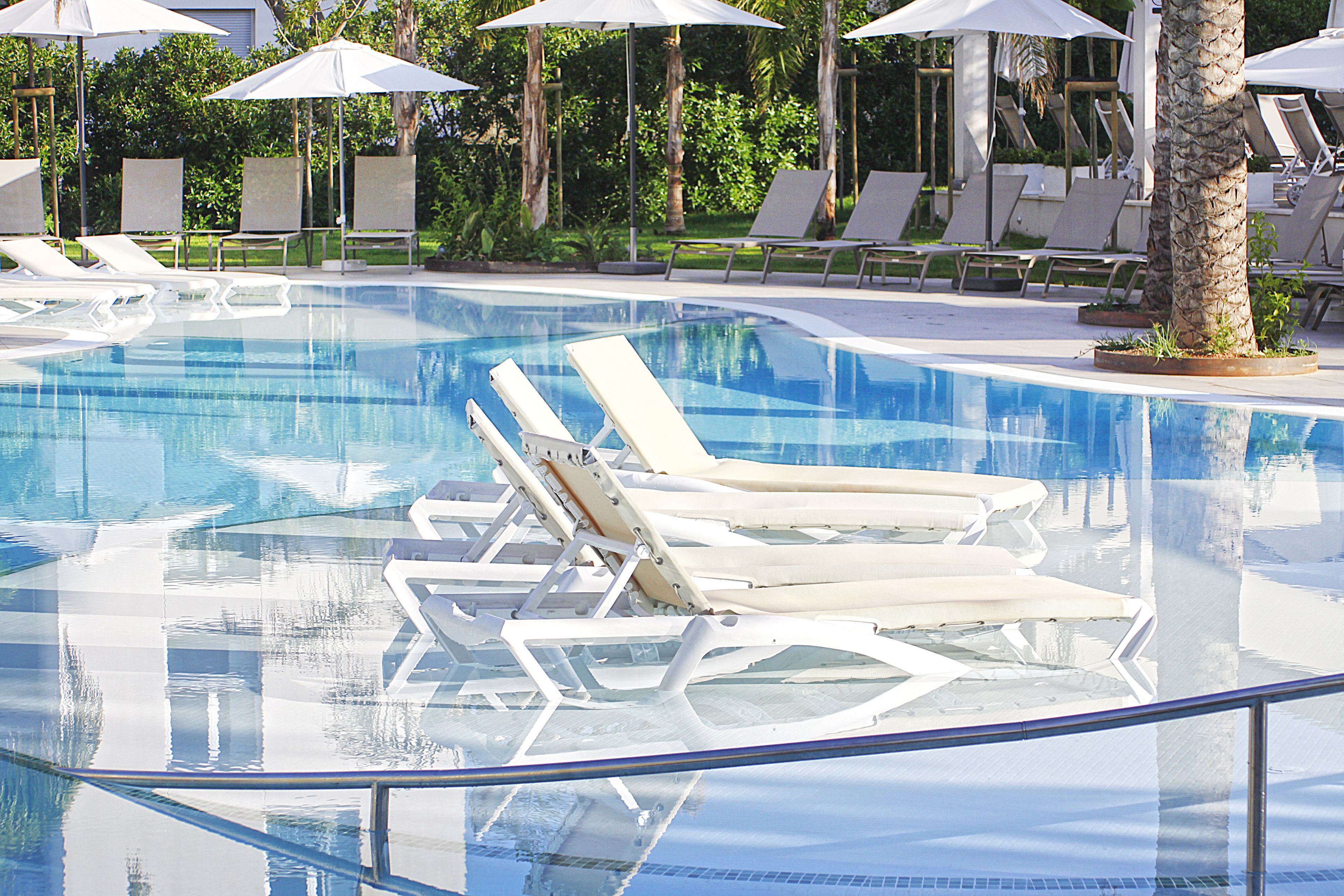 Una piscina limpia con sillas de descanso y sombrillas.