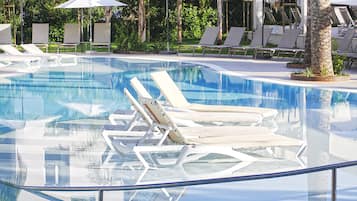 Una piscina limpia con sillas de descanso y sombrillas.