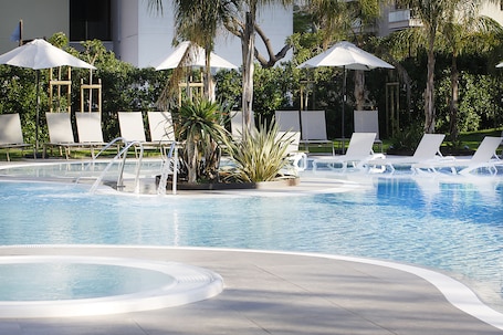 Una piscina techada, una piscina al aire libre, sombrillas
