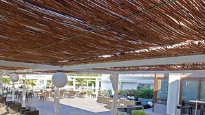 Un espace extérieur aménagé avec des meubles modernes, un toit de chaume et une vue sur le paysage environnant.