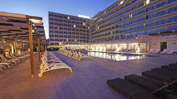 Een binnenzwembad, een buitenzwembad en parasols bij het zwembad