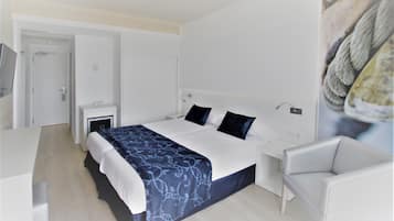 Ein modernes Hotelzimmer mit einem großen Bett, einem Nachttisch, einem Sessel und einer Tür.
