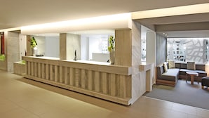 Ein moderner Empfangsbereich mit einer Marmor-Theke, Topfpflanzen und einer Sitzecke inklusive Sofa und kleinem Tisch.