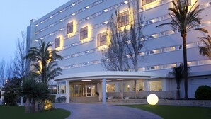 Ein modernes Hotel mit gebogener Eingangsparte, mehreren Etagen und einer gut beleuchteten Fassade.