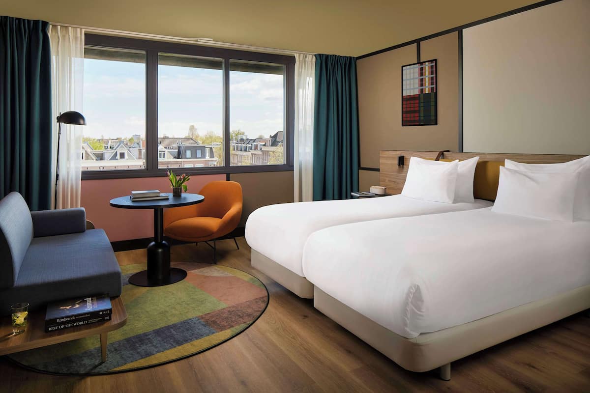 Une chambre d’hôtel avec un grand lit, un canapé, une petite table et une chaise.