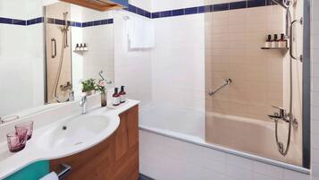 A modern bathroom with a bathtub, a shower area, and a vanity with a sink and mirror.