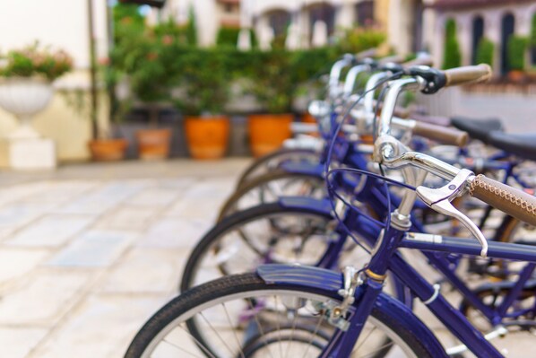 A row of bicycles parked in an outdoor area with potted plants and a tiled floor. - Avani Museum Quarter Amsterdam Hotel (Amsterdam)