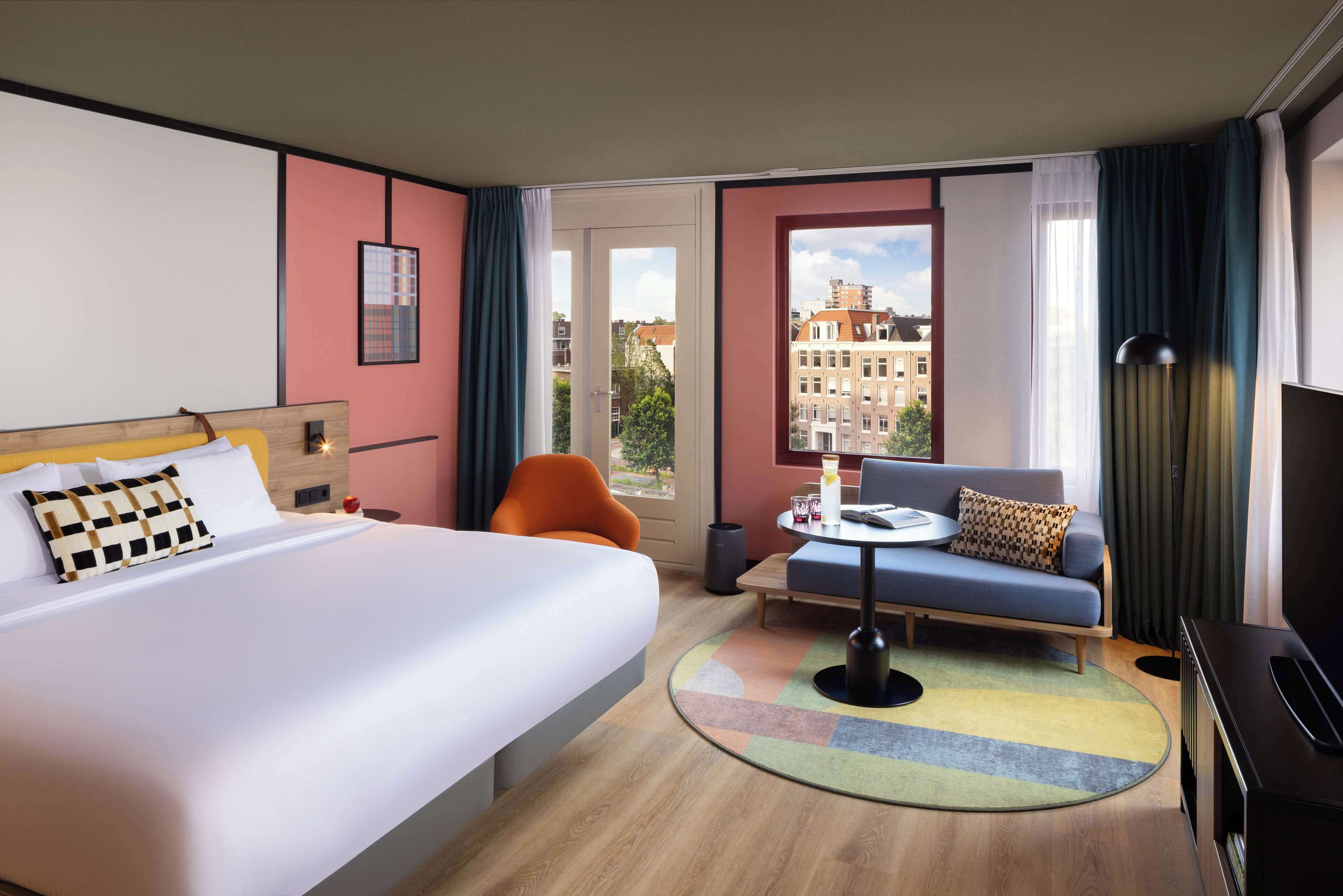 A hotel room with a large bed, a sofa, a small table, and a TV.