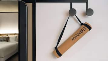 Une pièce comprenant un lit, un luminaire fixé au mur et un tableau d’affichage en liège sur lequel est accroché un objet enroulé, étiqueté « AVANIFT ».
