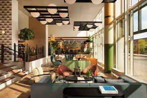 A modern lobby with a staircase, seating area, and large windows. - Avani Museum Quarter Amsterdam Hotel (Amsterdam)