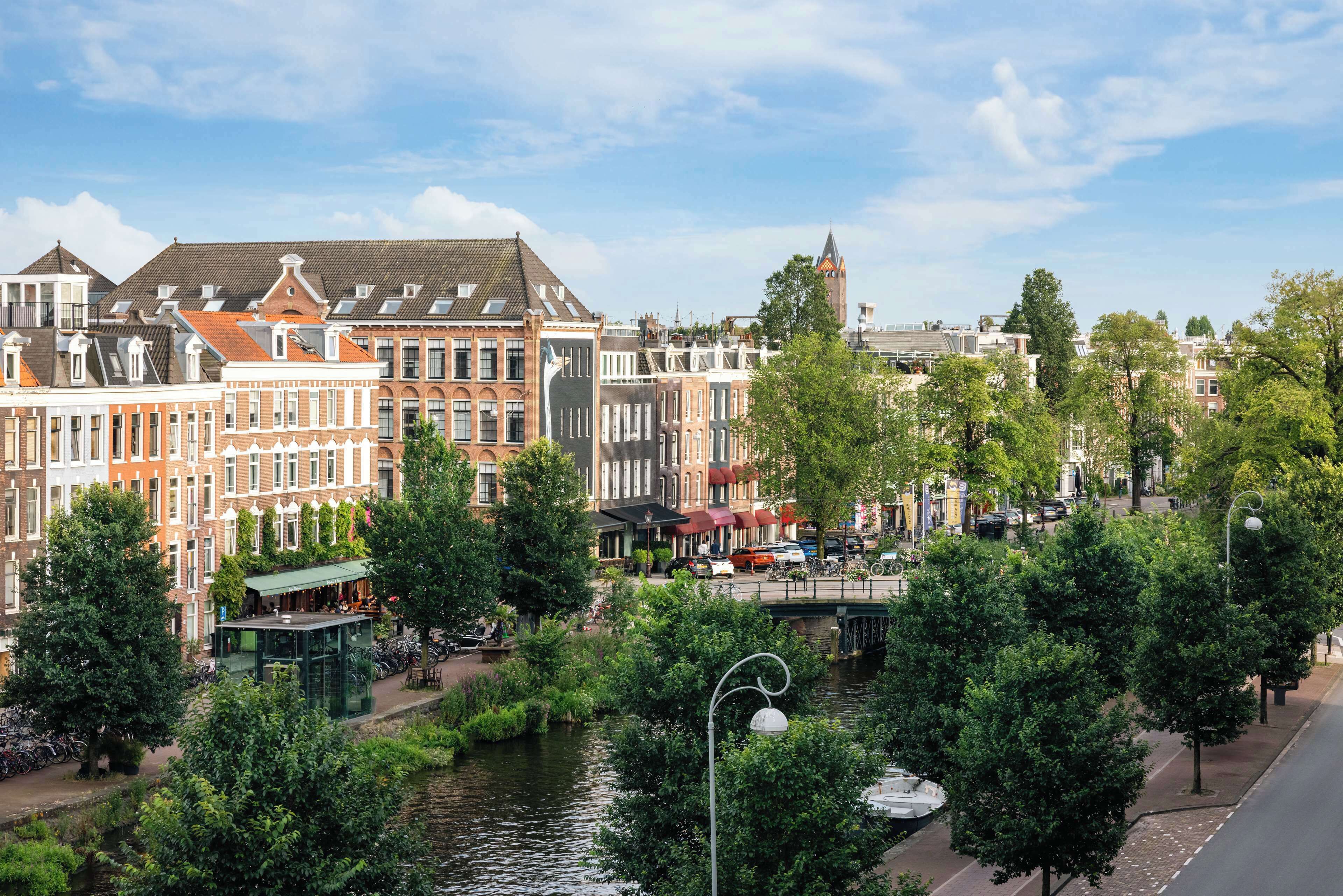 A canal-side view of historic buildings with a bridge and trees.