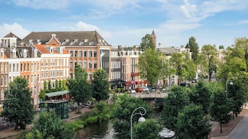 A canal-side view of historic buildings with a bridge and trees.