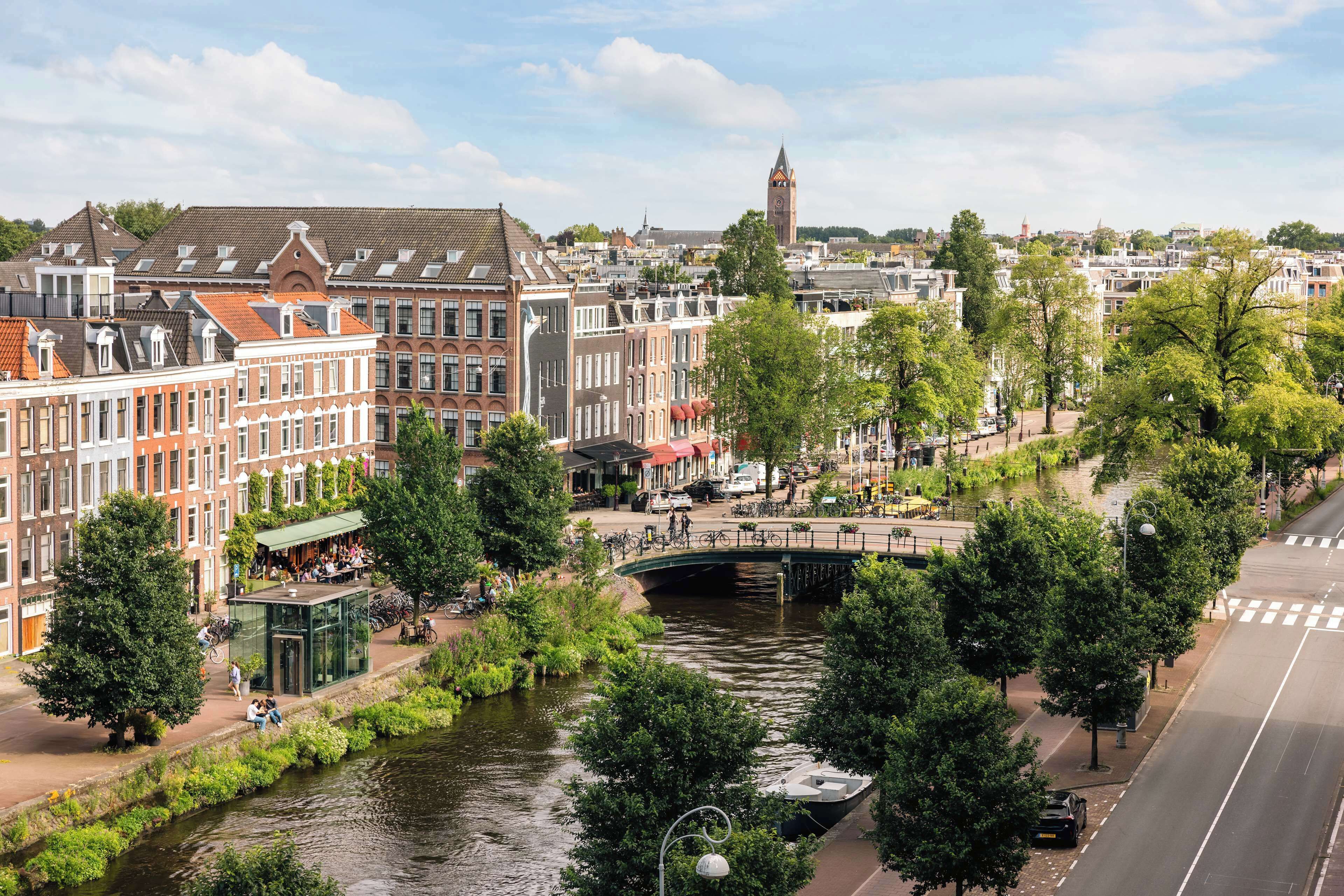 A canal with a bridge, surrounded by historic buildings and trees.