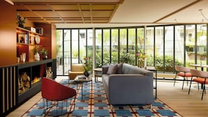 Un salon moderne avec une cheminée, un canapé, une table basse et une vue sur un jardin grâce à de grandes fenêtres.