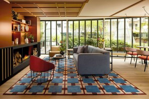 A modern living room with a fireplace, a sofa, and a dining area with chairs. - Avani Museum Quarter Amsterdam Hotel (Amsterdam)