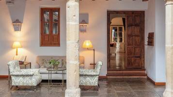 Un interior acogedor con un pilar de piedra, dos sillones estampados, una mesita y una puerta de madera que da a otra habitación.