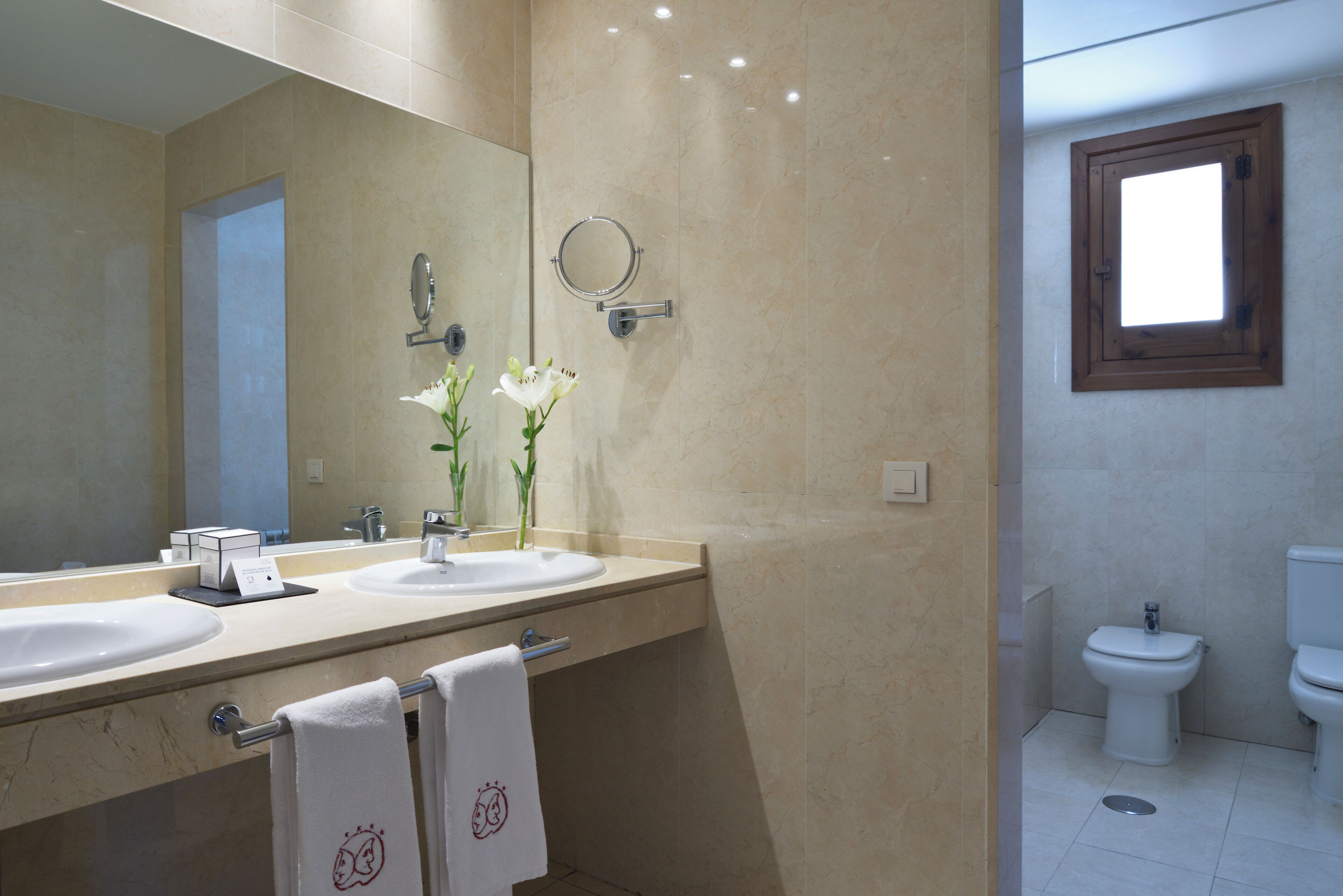 A bathroom with two sinks, a mirror, and a toilet.