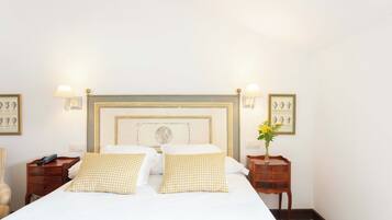 A neatly made bed with checkered pillows, a wooden headboard, and bedside tables with lamps and framed pictures.