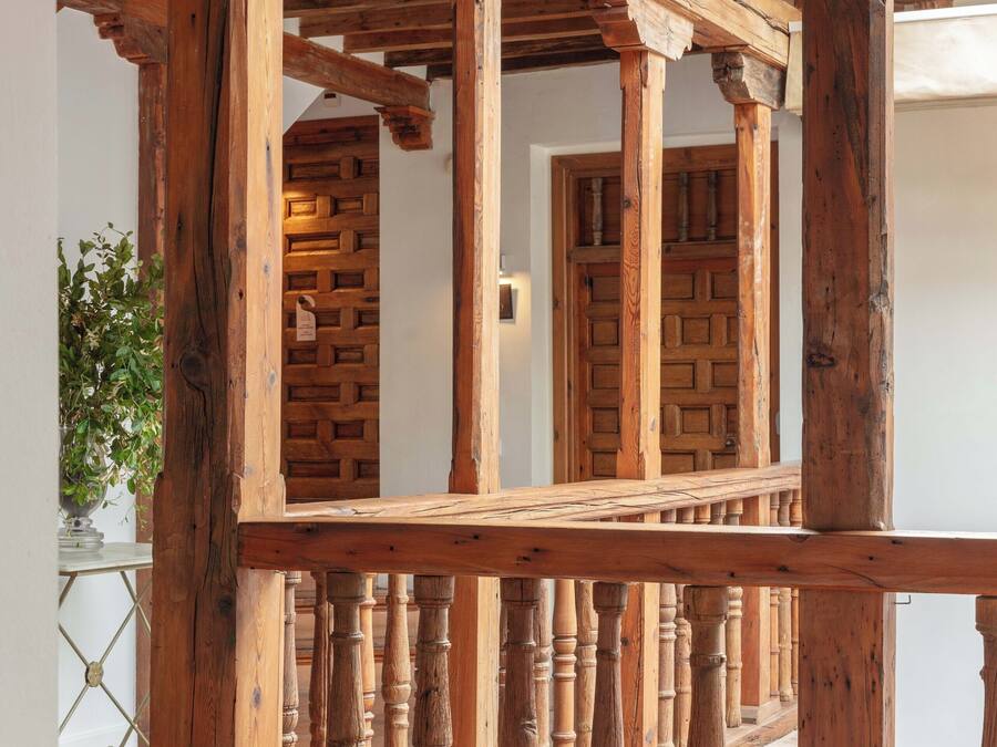 Un balcón de madera con barandilla, una escalera y un muro con diseño.