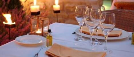 Ein Tisch, gedeckt für eine Mahlzeit, mit Kerzen, Gläsern und einer Olivenölflasche.