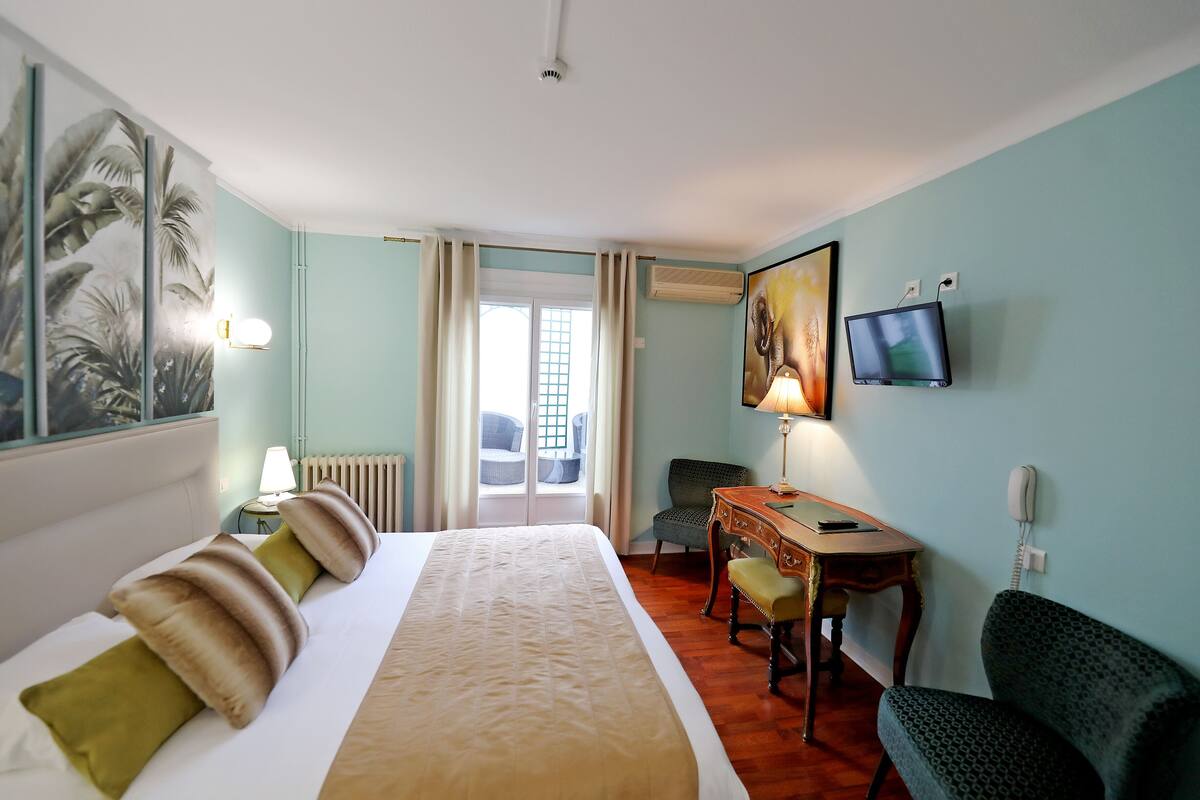 A hotel room with a bed, a desk, a chair, a television, and a window with curtains.