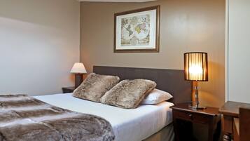 A hotel room with a large bed, two pillows, a lamp, and a framed map on the wall.